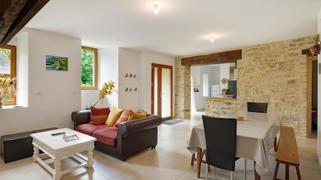 A modern living room with a sofa, coffee table, and dining area with chairs and a table.. Gite la longère – nature and tranquility