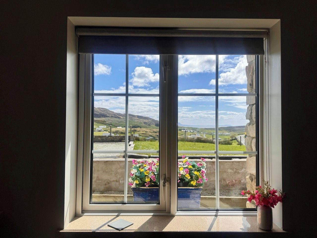 Ein Fenster mit Blick auf eine Landschaft, eine Tür und ein Blumentopf auf dem Fensterbrett.