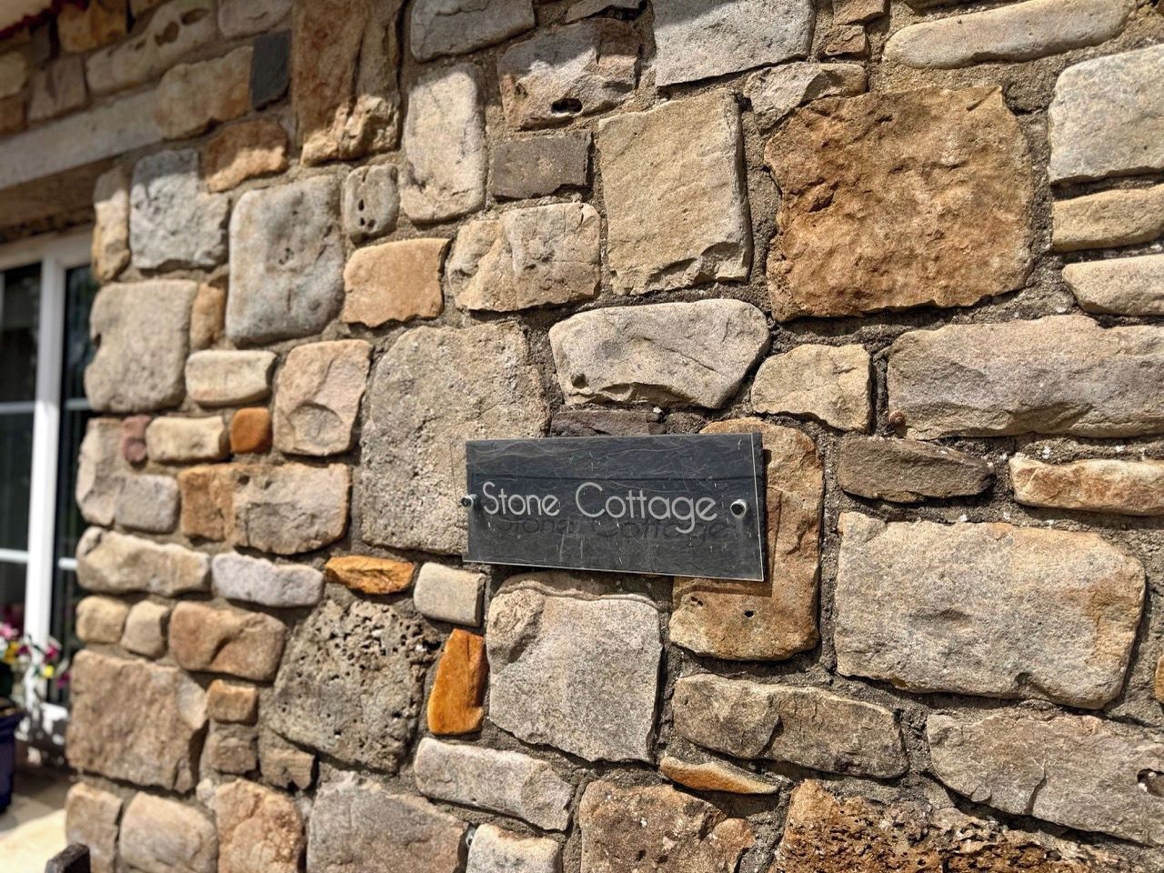 Mural de pedra com uma placa que diz 'Stone Cottage'.