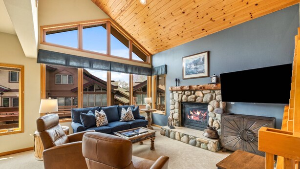 A cozy living room with a fireplace, leather furniture, and a large window. - Great Savings for Labor Day! A/C, Hot Tub, 2 En suites (Steamboat Springs)