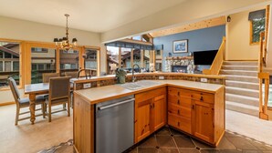 A kitchen with a dishwasher, wooden cabinets, a dining area with chairs, and a staircase. - Great Savings for Labor Day! A/C, Hot Tub, 2 En suites (Steamboat Springs)