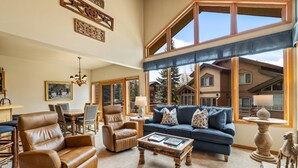 A spacious living room with a large window, leather armchairs, a blue sofa, and a wooden coffee table. - Great Savings for Labor Day! A/C, Hot Tub, 2 En suites (Steamboat Springs)
