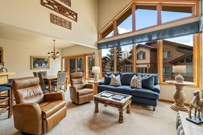 A spacious living room with a large window, leather armchairs, a blue sofa, and a wooden coffee table. - Great Savings for Labor Day! A/C, Hot Tub, 2 En suites (Steamboat Springs)