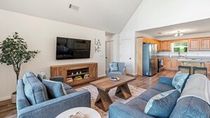 A living room with a sofa, coffee table, TV, and a bookshelf. - The Lake Escape, Sleeps 8, Big Deep Water, Kayaks, Lily Pad + MORE! (Sparta)