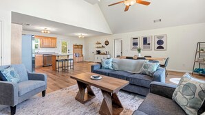 A spacious living area with a high ceiling, a dining table, a sofa, and a kitchen in the background. - The Lake Escape, Sleeps 8, Big Deep Water, Kayaks, Lily Pad + MORE! (Sparta)