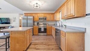 A modern kitchen with wooden cabinets, stainless steel appliances, and a granite countertop. - The Lake Escape, Sleeps 8, Big Deep Water, Kayaks, Lily Pad + MORE! (Sparta)