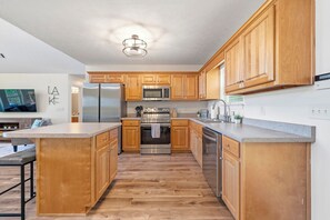 Une cuisine moderne avec des meubles en bois, des appareils en acier inoxydable et un plan de travail en granit.