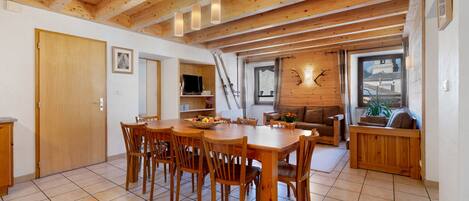A wooden interior with a dining table and chairs, a sofa, and a fireplace.