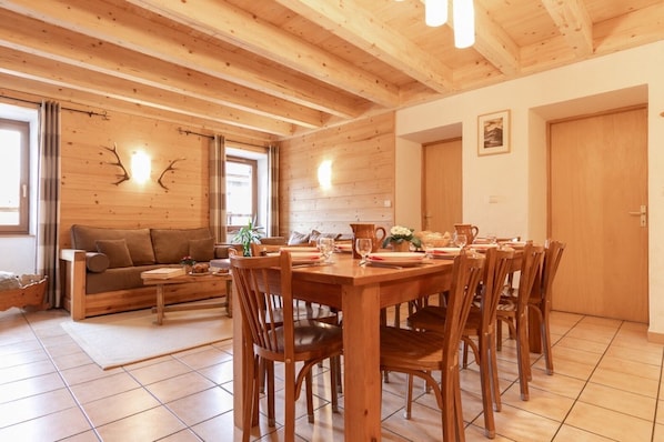 Ein Holzinterieur mit einem für vier Personen gedeckten Esstisch, einem Sofa und einer an der Wand befestigten Uhr.