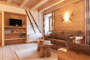 Un intérieur en bois avec une télévision, des skis, un canapé et une table avec des tasses.