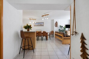 A modern kitchen with a dining area, a bar stool, and a wooden bench.