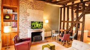 A cozy living room with exposed wooden beams, a fireplace, a bookshelf, and a comfortable seating area. - T3 rénové avec charme, 2 chambres cœur Tours (Tours)