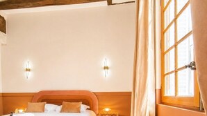 A hotel room with a bed, bedside table, lamp, chair, and a window with curtains. - T3 rénové avec charme, 2 chambres cœur Tours (Tours)