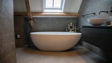 A modern bathroom with a freestanding bathtub, a large mirror, and a skylight.