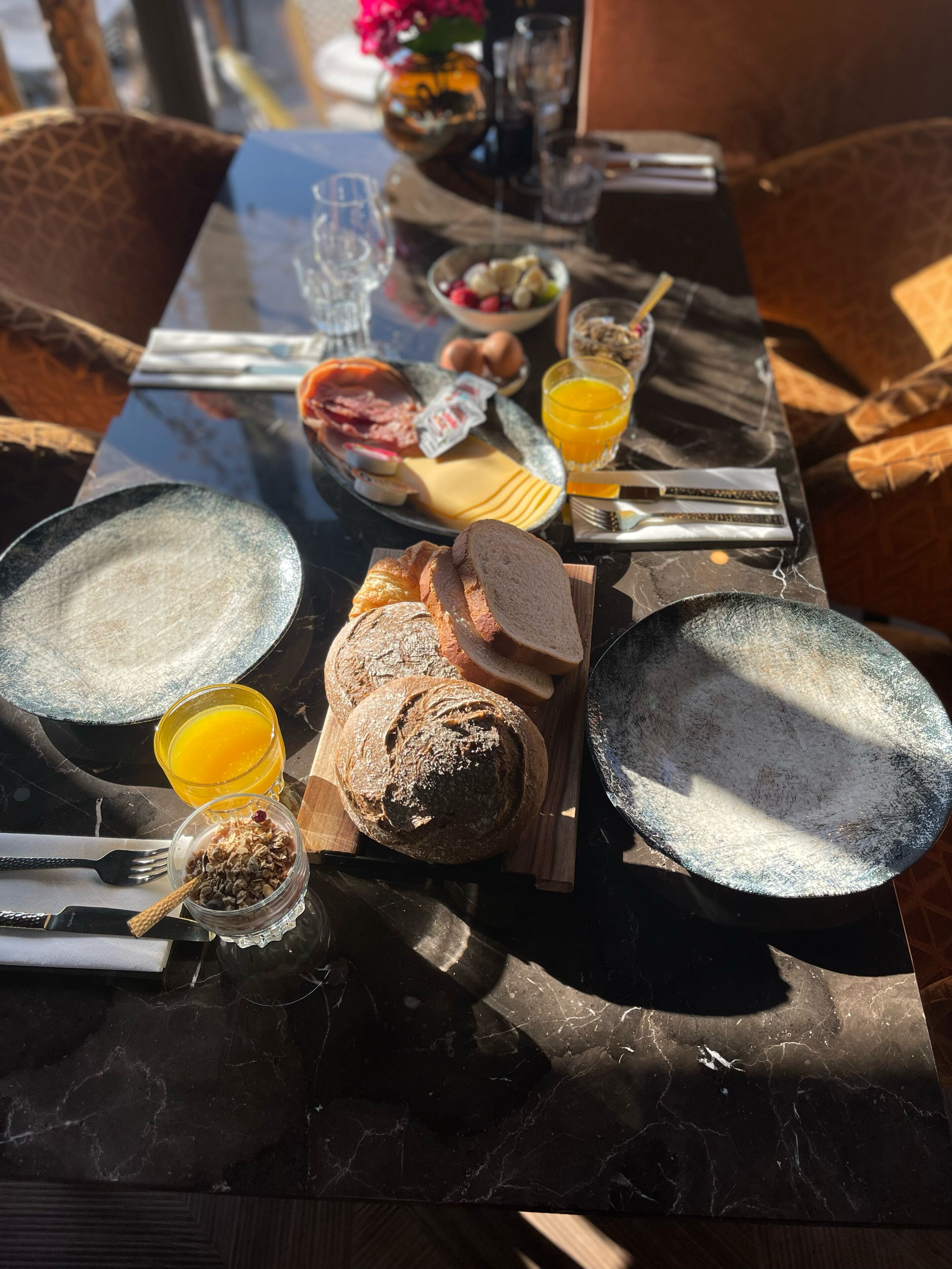 Een ontbijttafel met borden, brood, eieren en sap.