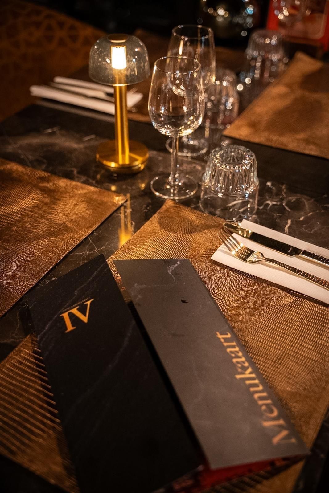 A table set with wine glasses, a candle, and a menu.