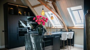 A modern kitchen with a marble island, black cabinetry, and a skylight. - Room4 (Maurik)