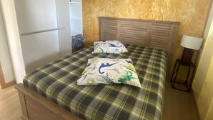 A bedroom with a bed, a wardrobe, a headboard, and a bedside table. - Bungalow Le Sapotille (Saint-Paul)