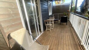 A wooden deck with a white chair, a table, and a hanging light fixture. - Bungalow Le Sapotille (Saint-Paul)