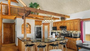 Una cocina amplia con armarios de madera, una isla central con taburetes de bar y una zona de comedor con mesa y sillas.