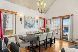 Un coin repas avec une table en bois, des chaises et un lustre.