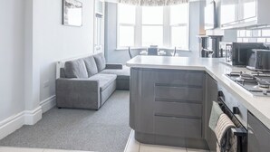 A modern kitchen with a grey island, white cabinets, and a large window. - Cosy 2-Bed apartment | sleeps 6 | Sea views - Pass the Keys (Southend-on-Sea)