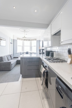 A modern kitchen with a central island, built-in appliances, and a dining area with a sofa.
