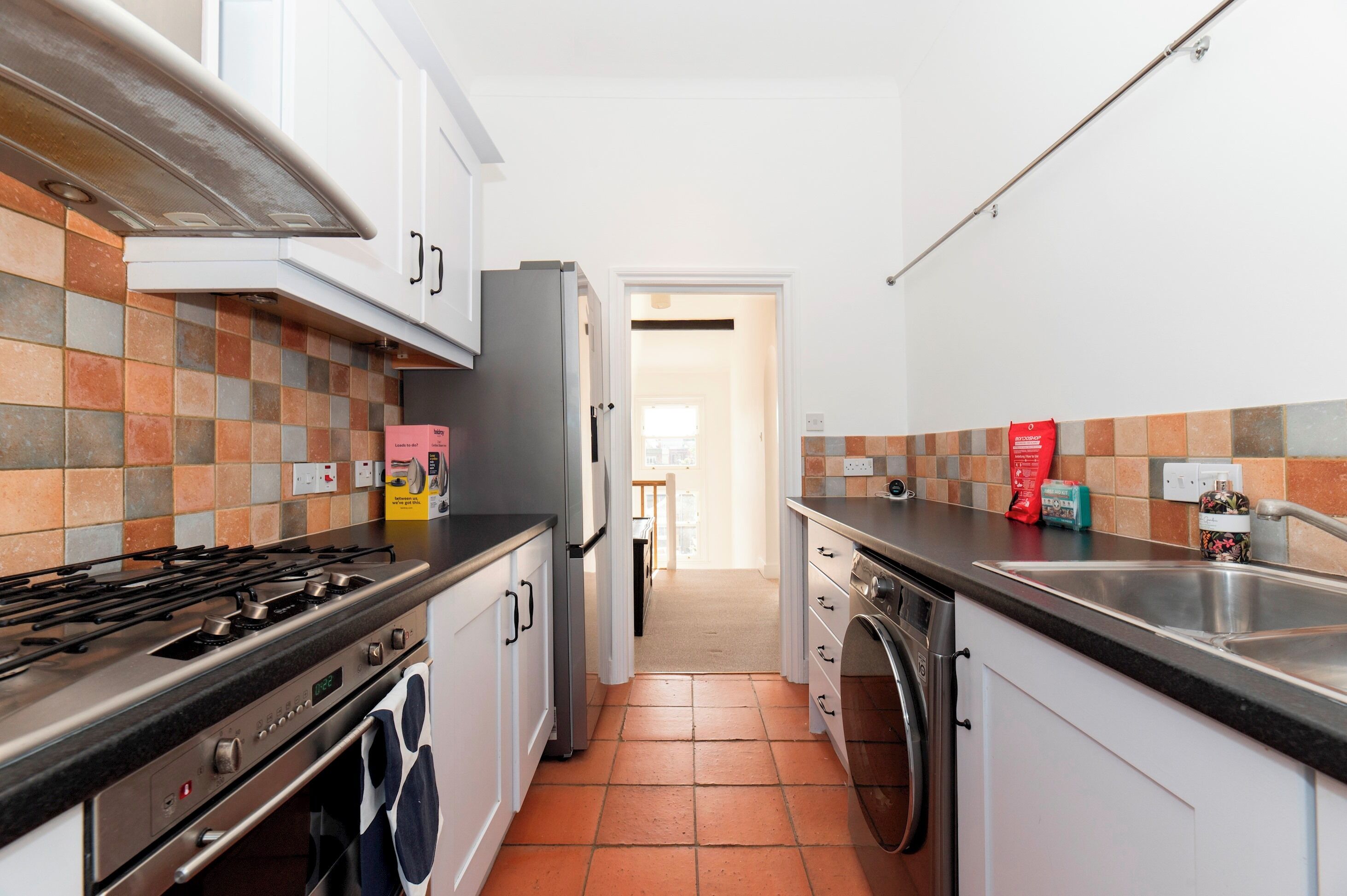 Eine Küche mit Gasherd, Backofen, Kühlschrank und Waschmaschine.