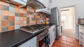 Eine Küche mit Gaskochfeld, Backofen und gefliestem Fliesenspiegel.