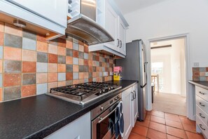 Eine Küche mit Gaskochfeld, Backofen und gefliestem Fliesenspiegel.