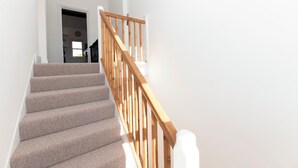 Eine Treppe mit Teppichstufen und Holzläufer, die zu einem Innenraum führt.