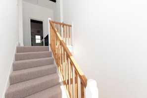 Una escalera con peldaños alfombrados y barandillas de madera que conduce a un espacio interior.