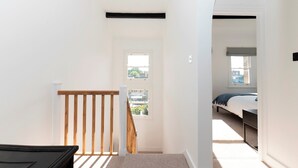 Ein Schlafzimmer mit Bett, Fenster und Ausblick nach draußen.