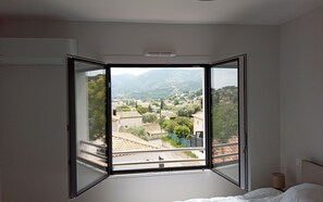 Ein Schlafzimmer mit großem Fenster, einem Bett und einem Nachttisch.