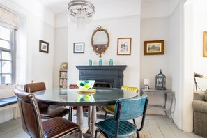 Un comedor con una mesa redonda, sillas, chimenea y obras de arte enmarcadas en las paredes.