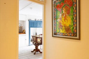Un comedor con una mesa y sillas de madera, un armario azul y una obra enmarcada en la pared.