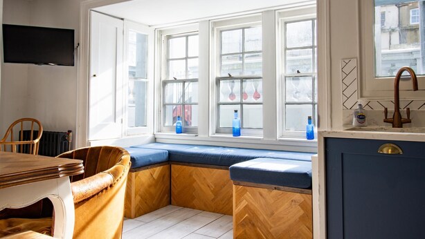 Una cocina con una banca integrada, una mesa de comedor y un televisor instalado en la pared.