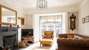 Una sala de estar con chimenea, televisor, sofá, sillón y un espejo grande.