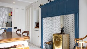 Una habitación con pared de diseño espiga, chimenea azul, radiador de latón y mesa de comedor de madera con sillas.