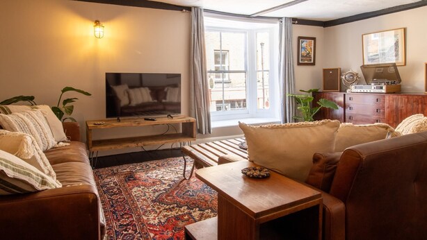 Un salon comprenant un téléviseur, un canapé, une table basse et un tapis à motifs.