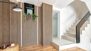A modern interior with a wooden slatted wall, a staircase, and a hanging pendant light. - Casa Arizona – Central Duplex Puerto Rico GC (Puerto Rico de Gran Canaria)