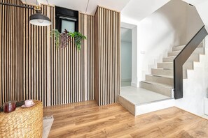 A modern interior with a wooden slatted wall, a staircase, and a hanging pendant light. - Casa Arizona – Central Duplex Puerto Rico GC (Puerto Rico de Gran Canaria)