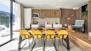 A modern kitchen with a dining area, large windows, and a view of the outdoors. - Casa Arizona – Central Duplex Puerto Rico GC (Puerto Rico de Gran Canaria)