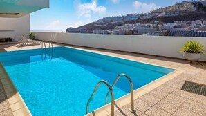 Piscina no terraço com vista para uma vila na encosta.