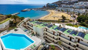 Hotel à beira-mar com piscina, acesso direto à praia e painéis solares nos telhados.