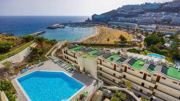 A hotel with a swimming pool, beach access, and a view of the ocean.