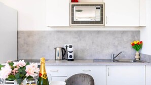 Eine moderne Küche mit Mikrowelle, Wasserkocher und Toaster auf der Arbeitsfläche, einem Spülbecken und einem Essbereich mit Tisch für zwei Personen.