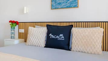 A hotel room with a bed, a wall-mounted artwork, a vase with flowers, and a bedside table.