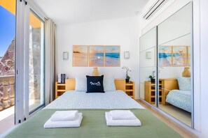 Ein Hotelzimmer mit einem Bett, zwei Nachttischen, einem großen Fenster und Kunstwerken an der Wand.
