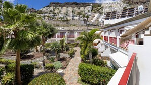 Un hôtel situé sur une colline, avec un sentier menant à l’entrée, entouré d’une végétation luxuriante et de palmiers.